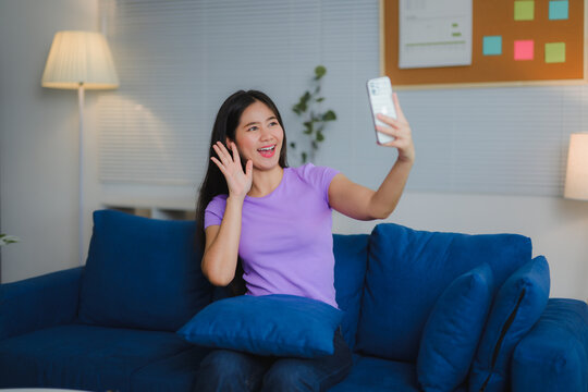 Young woman waving while video calling with smartphone at home