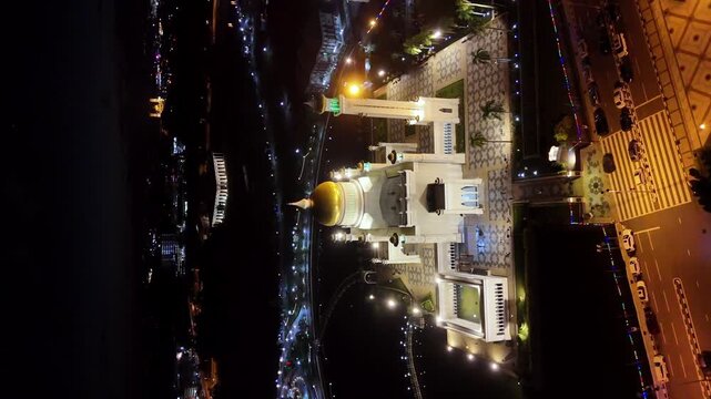 Cinematic night aerial drone shot of the Omar Ali Saifuddien Mosque in Brunei. Cinematic vertical aerial shot, rotating slowly.