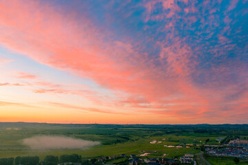 Fototapeta premium Expansive Grassland under Radiant Sunset Sky Filled with Evening Clouds