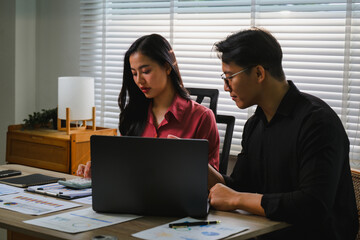 Obraz premium Asian business people analyzing financial data using laptop and calculator in office