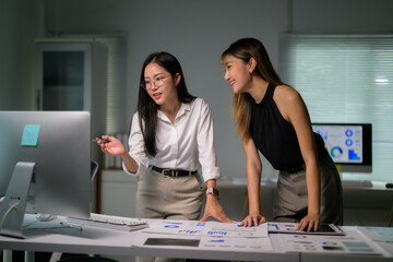 Asian businesswomen discussing over financial reports showing data on computer screen in meeting room © PaeGAG