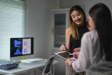Businesswomen discussing marketing strategy using clipboard and digital tablet in office
