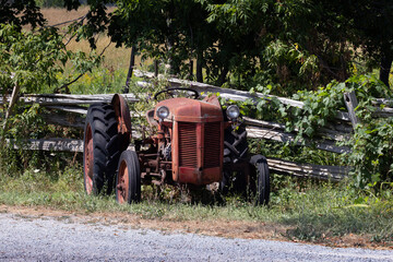 Rusty red antique farming tractor left to weather under the elements