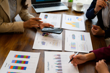Businesswomen analyzing sales reports using smartphone and printed documents