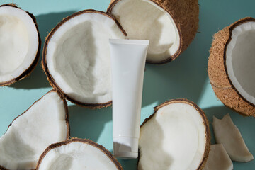 A fresh white cosmetic tube surrounded by coconuts, decorated on blue background. The focus is on natural ingredients, showing coconut’s role in clean, pure beauty products.