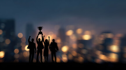Team member is honored with applause, holding a trophy that embodies success, as business professionals celebrate corporate achievement under city lights at night.
