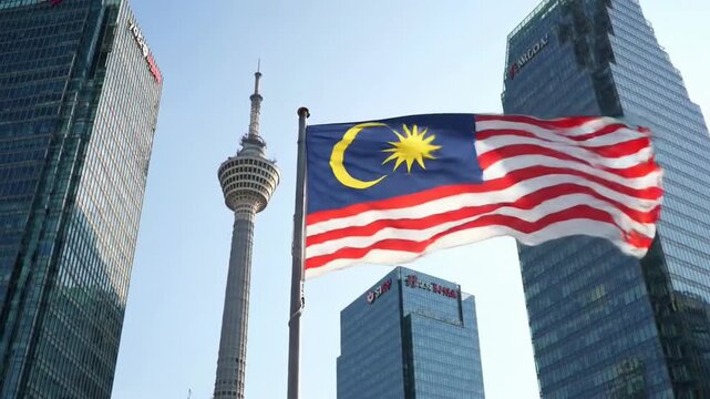 Malaysia's flag waves proudly against the iconic backdrop of the Kuala Lumpur Tower and modern architecture 