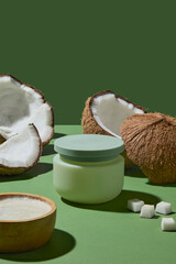 A tall white cream jar surrounded by coconuts decorated on green background. This image shows how coconut serves as the heart of skincare, offering moisture and natural benefits.