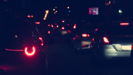 Abstract environment of traffic jam on the road at night. Rear side of car with turn on light. Red glow of car taillights shines brightly at night.