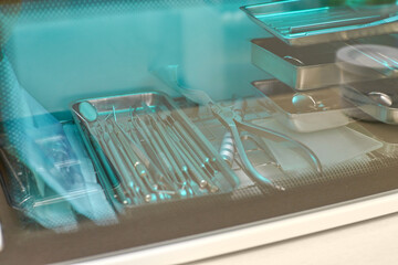 Sterilized dental tools in clean medical tray under protective glass surface in dental clinic.