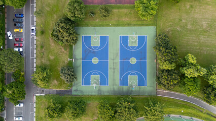 Aerial View of Two Outdoor Basketball Courts Surrounded by Lush Green Trees and Parking Lot