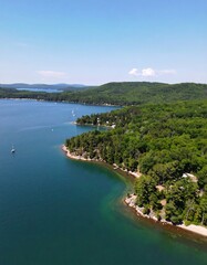 Fototapeta premium Aerial view of a tranquil bay, lush green hillsides meeting clear, teal water, dotted with sailboats