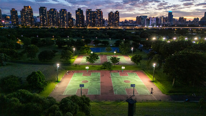 Illuminated City Park Basketball Courts at night with Skyline View