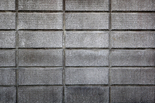 Close-up of a grey concrete block wall with rectangular patterns and rough surface texture.