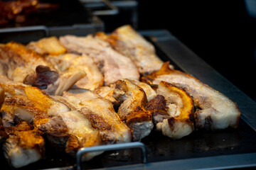 pork belly slices being pan-fried or grilled