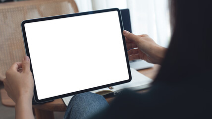 Mockup image of woman using digital tablet with blank white screen during working with laptop computer at coffee shop, close up. Mockup tablet for online marketing or web template