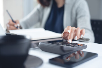 Close up business woman using calculator to calculate home finance and working on laptop computer, calculate expenses, business finance and investment, budget management