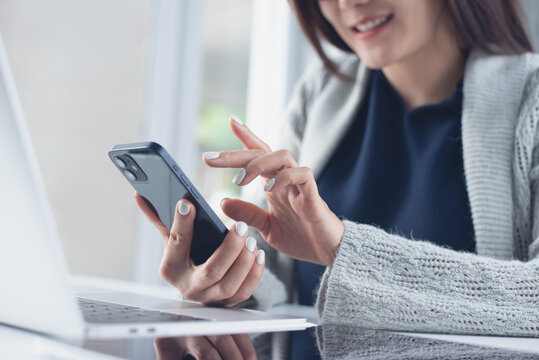 Happy asian business woman using smartphone, online working on laptop computer, surfing the internet, searching the information at office. - Powered by Adobe