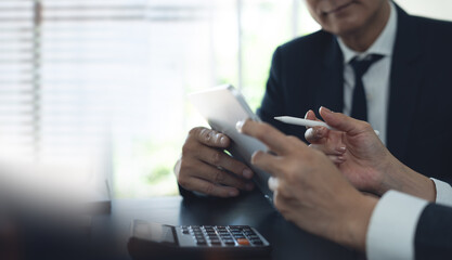 Businessman having a discussion with colleague, working together in office. Two asian business people using digital tablet at meeting. teamwork and collaboration