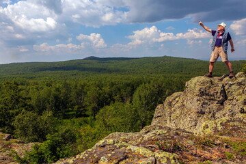 Naklejka premium mature man tourist standing on top of cliff on ural ridge irendik sunny summer day