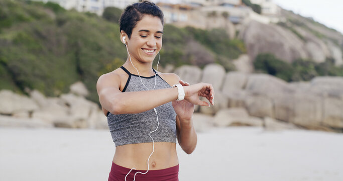 Fitness, earphones and woman with smart watch at beach for heart rate, exercise information or pulse. Music, happy runner and check wristwatch for wellness stats, timer and tracking pace outdoor