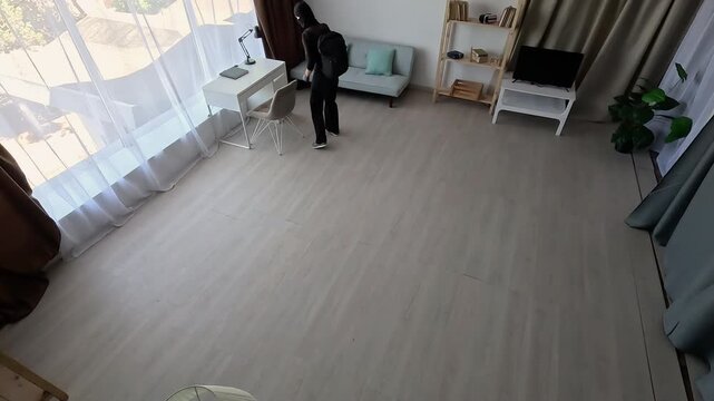 burglar in black balaclava breaking into home, CCTV surveillance security camera. Theft, crime and robbery