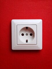 of a recessed European socket on a red wall, with flat background and crisp white edges for visual contrast recessed European socket red wall background contrast white edge primary color clean 