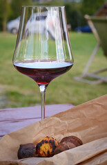 Glass of red wine with chestnuts on table outdoors