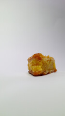 Piece of moist yellow cake with golden crust on white background