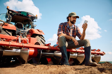 Below view of farmer using smart phone while taking a break from working in the field.