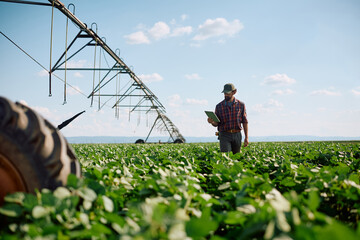 Agriculturist using touchpad while inspecting the corps on his farm.
