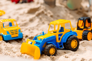A group of toy trucks are on a sandy beach