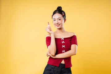 Smiling woman with lipstick in hand posing against a solid yellow backdrop Beauty and makeup