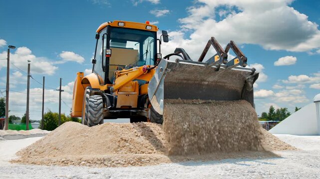 Yellow excavator front loader unloads gravel in front of a modern warehouse, cascading stones and dust, showcasing precise earthmoving power, industrial control, and realistic motion.