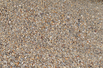 Small pebbles on the shore in a beach on sunny day, viewed from above. Abstract natural travel, vacation and summer background.