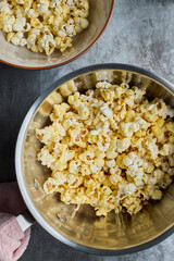Top view of popcorn making in a pot and popcorn in a bowl on an old tray.