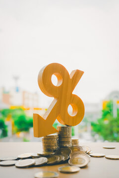 Wooden percent symbol with a downward arrow on coins represents decreasing interest rates, lower mortgage costs, and improved loan conditions. Perfect for banking, investment, or finance news visuals.