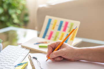 Teacher writing on clipboard while planning school activities using a flow chart made with sticky notes and a pencil, promoting organization, education, and successful learning