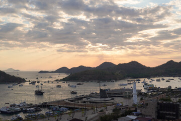Fototapeta premium Scenery of Labuan Bajo harbor with boat sailing in the ocean and the cityscape, Indonesia tourist destination.
