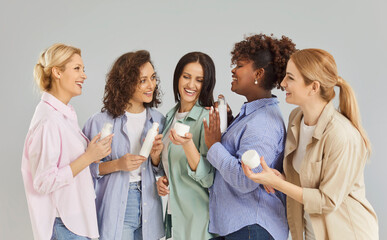 Beautiful multi ethnic friendly group of happy women holding bottles mockup for body treatment, spa...