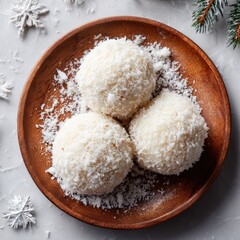 Three coconut balls on wooden plate, snowy background