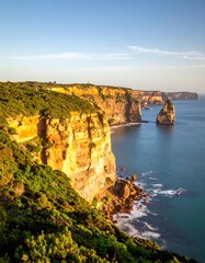 Coastal cliffs bathed in golden sunlight, waves gently lapping the shore