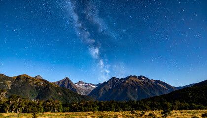 Obraz premium Night Sky Landscape Over Mountain Range with Green Foliage and Starry Galaxy in the Background