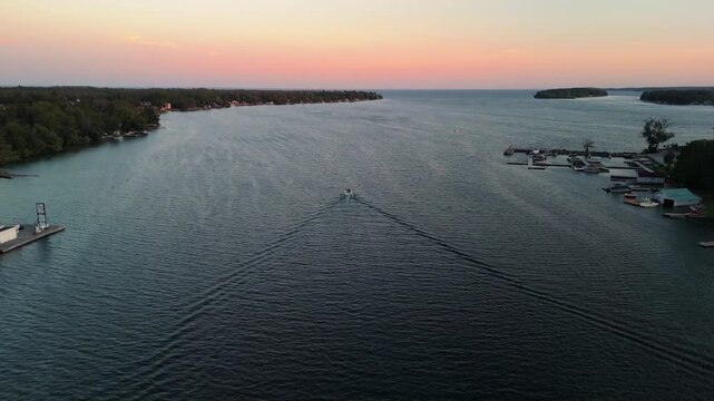 Aerial footage of a fishing boat sailing on the tranquil lake Simcoe at sunset in Atherley, Canada