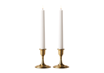 Two white pillar candles in brass candle holders