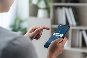 Close-up of a person using a smartphone with a smart home app. Finger poised to tap, symbolizing seamless IoT connectivity, remote control, security, and energy-efficient comfort in daily life