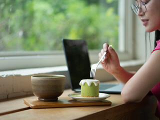 Working at cafe, A matcha mousse cake with cream topping, served on a small plate and wooden tray in warm tones