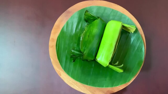 4K overhead spin of lemper on banana leaf plate. Steamy sticky rice and savory chicken scent captured in motion. Great for culinary, tradition, lifestyle, and celebration themes.