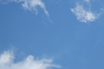 Bright blue sky with fluffy white clouds scattered across the horizon, creating a serene atmosphere ideal for backgrounds or design projects with copy space