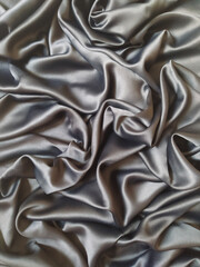 Fototapeta premium Luxurious silver silk fabric with elegant folds and flowing drapes texture background
